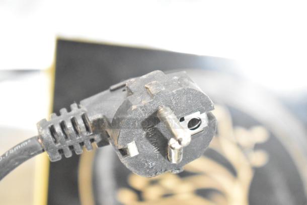 Close-up of a power plug from a countertop single burner induction range. Plug shows wear. Cooktop crack not visible.