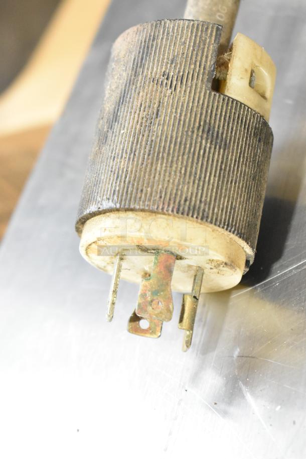 Close-up of a corroded electrical plug with a metal pronged base, details indicating wear and rust.