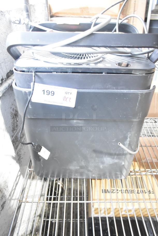 Two fans including a Midea, in used condition, stacked on a metal wire shelf. Label shows item number 199, quantity 2.