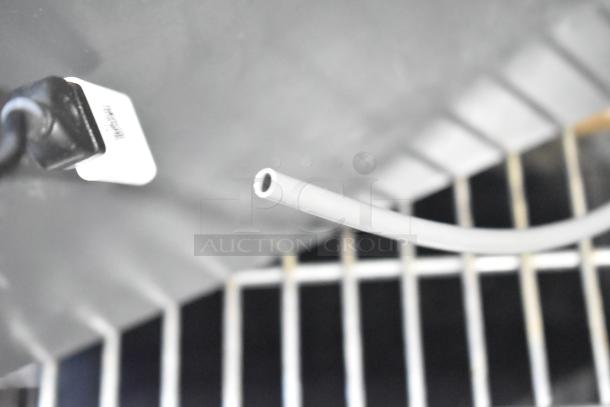 Close-up of a fan component with a visible cord and part of a fan grill. Includes Midea fan model. Black and white colors.