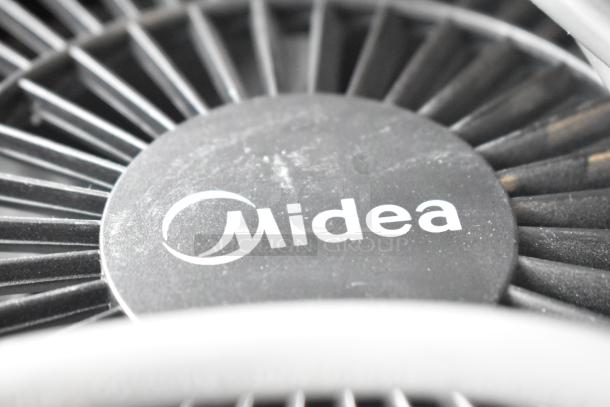 Two various fans, including one Midea fan, photographed in good condition. Midea logo visible on the fan casing.