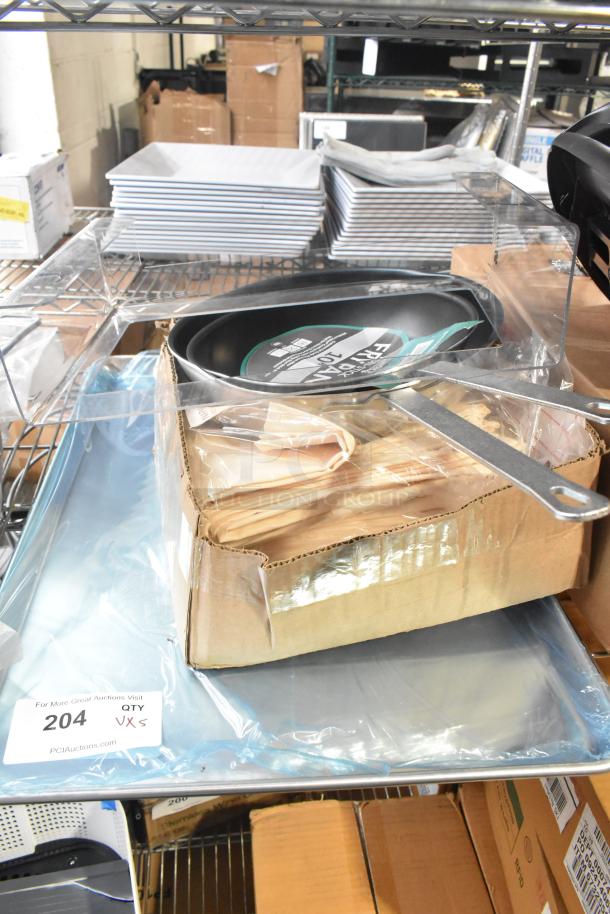 Brand new items including 10" and 12" Choice non-stick fry pans, Intedge ivory cloth napkins, and 19GA bun pans, in packaging.