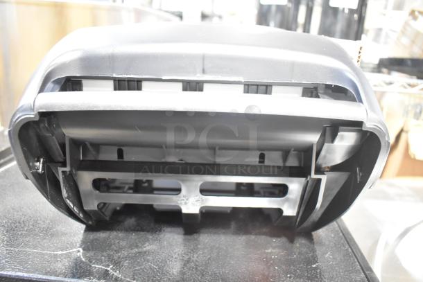 Brand new Bio-Kleen poly wall mount paper towel dispenser with minor scratches and dents, black plastic exterior.