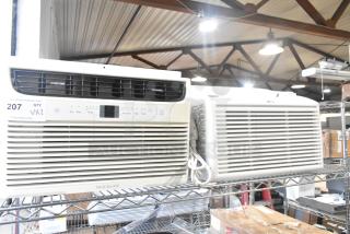 Two window mount air conditioning units, LG and Frigidaire, on display. Features include adjustable vents and controls.