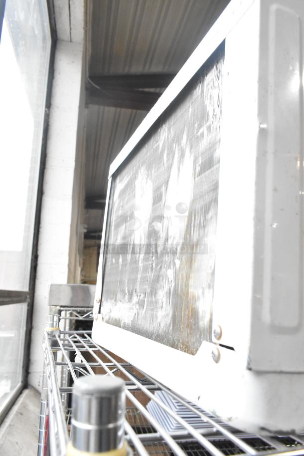 Two window mount air conditioning units, one by LG and the other by Frigidaire, shown side by side on shelving in used condition.
