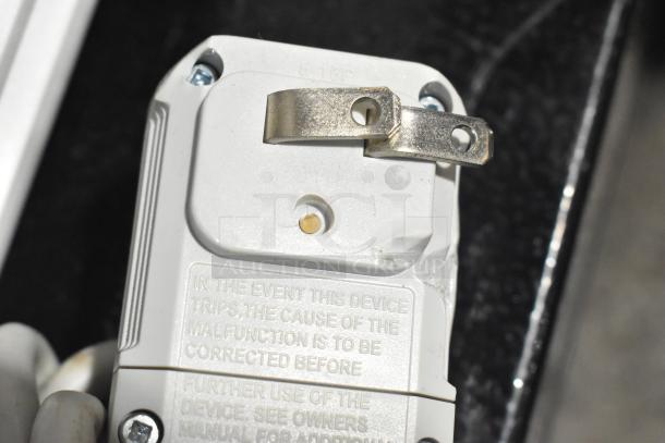 Close-up of a white, used power plug showing safety instructions and a metal bracket; text indicates corrective measures.