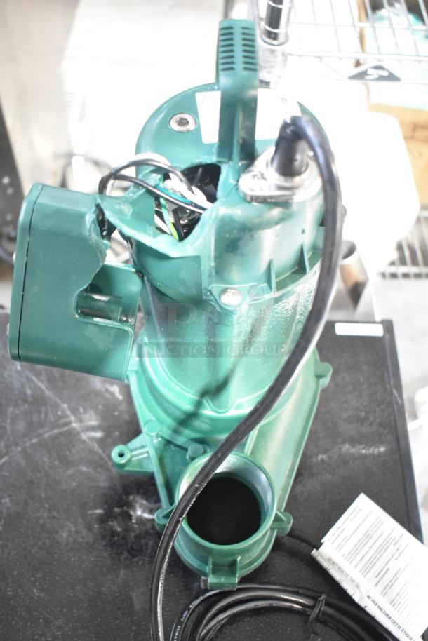 BRAND NEW Zoeller 212-0001 M212 Sewage Pump, 115V, showing minor cosmetic dents. Durable green casing with attached power cord.
