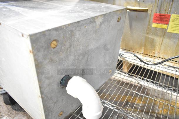 Set-n-serv Drop Ice Bin, metal exterior, visible wear and rust. Fitted with white PVC pipe. Used condition on wire rack.