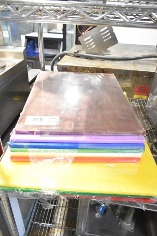 Stack of 12 brand new Choice cutting boards, multiple colors, sizes 20"x15" and 24"x18", tag reads "215 QTY V12."
