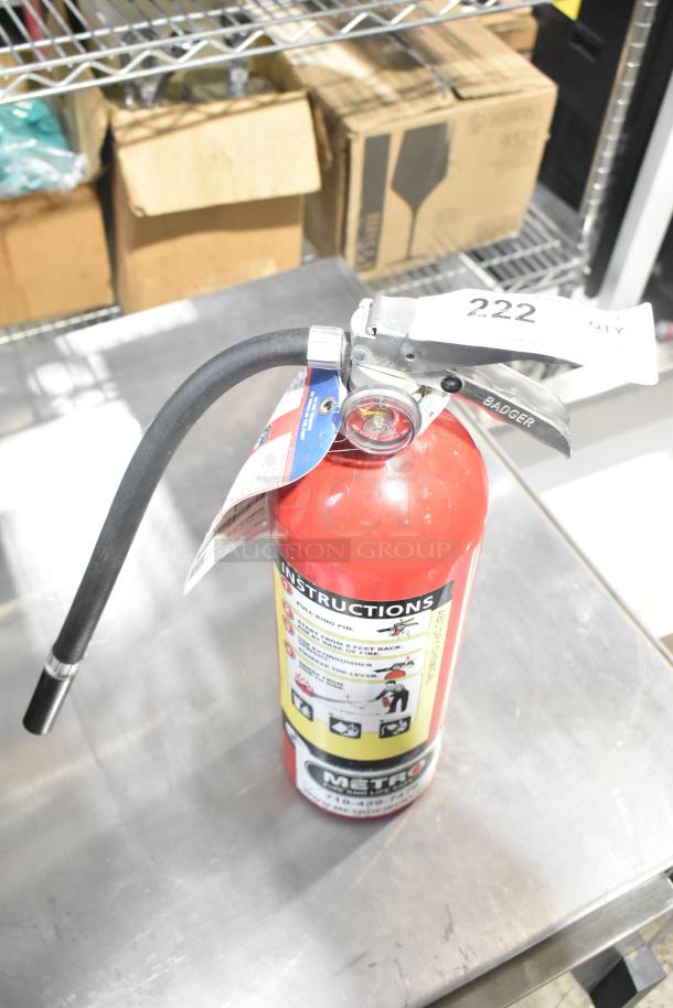 Red Badger fire extinguisher with instructional label, pressure gauge, and attached nozzle. Pickup only.