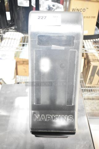 Black and clear poly countertop napkin dispenser in good condition, with "NAPKINS" label on front and item tag marked "227".