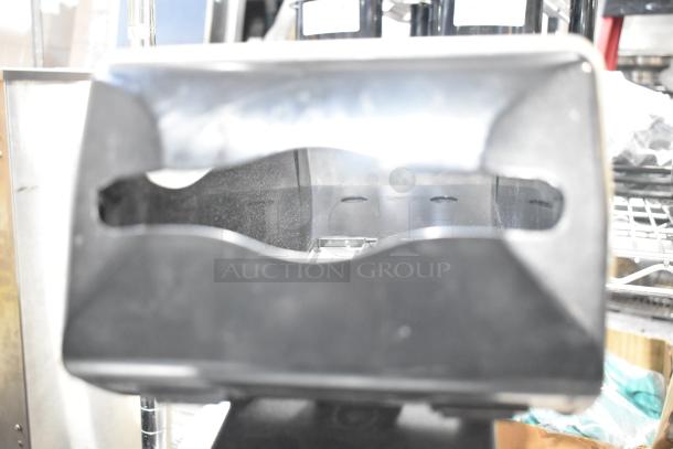 Black and clear poly countertop napkin dispenser, good condition, with front dispensing slot and durable plastic construction.