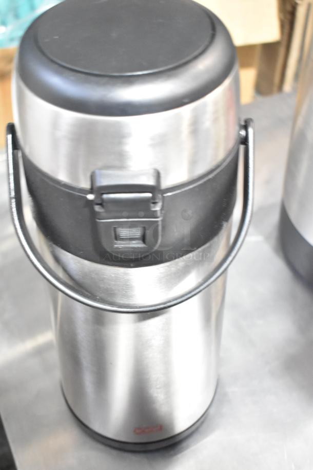 Stainless steel Oggi air pot with black lid and handle, suitable for hot beverages. Visible Oggi logo on the bottom.