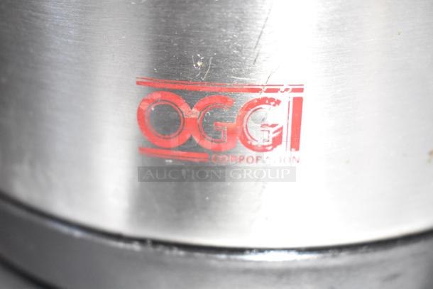 Oggi Air Pot close-up showing logo on stainless steel surface. Part of auction lot including Hamilton Beach and Bunn items.