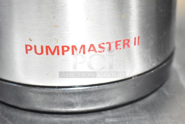 Zoomed-in view of stainless steel surface with red "PUMP MASTER II" text, part of an Oggi Air Pot.