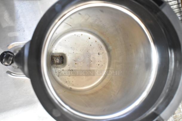 Interior view of a stainless steel beverage dispenser, showing slight residue, likely from Hamilton Beach. Moderate use visible.