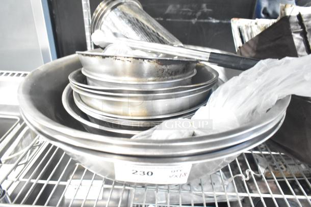 Stack of metal bowls and containers on a wire shelf, labeled "230 QTY x18," indicating 18 items in used condition.
