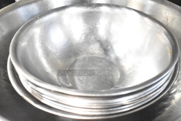 Stack of shiny metal bowls, some slightly scratched, part of a lot of 18 various items. Auction bid multiplies by 18.