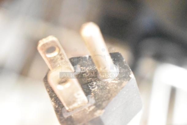 Close-up of Rancilio Rocky Doser grinder power plug, 115 volts. Visible wear on prongs. No other features visible.