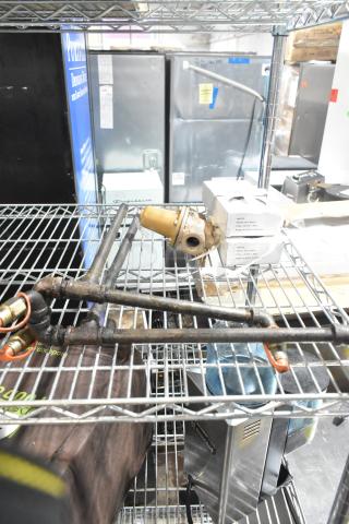 Variety of industrial items on metal shelf; includes Watts unit, pipe with Ansul tips, and gauges. Some rust and wear visible.