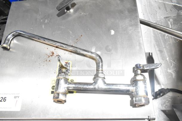 Stainless steel faucet with handles, moderate wear, for auction. Features QR code label, item number tag visible.