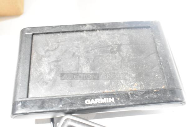 Four items including three Garmin GPS units, visibly scratched and dusty. "Garmin" logo on the bottom frame.