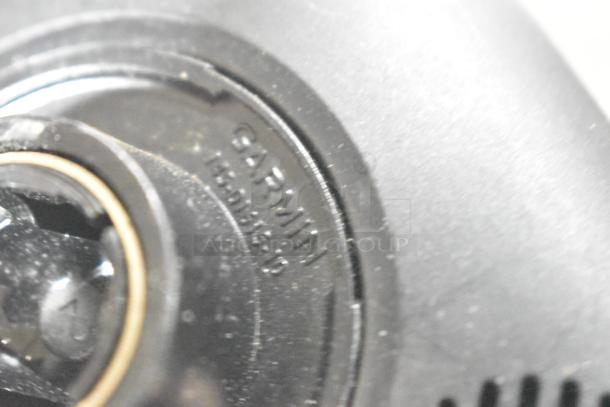 Close-up of a Garmin GPS device showing the brand marking, indicating authenticity. Condition appears used with some dust.