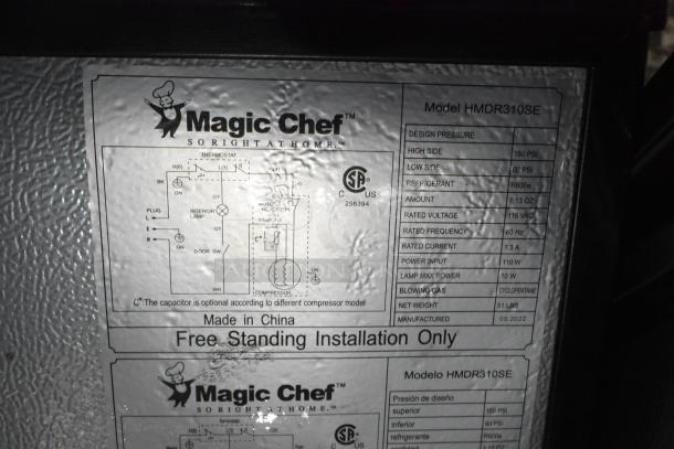Magic Chef HMDR310SE Mini Cooler with freezer label, detailing specs: 115 volts, 1 phase, R600a refrigerant, freestanding.