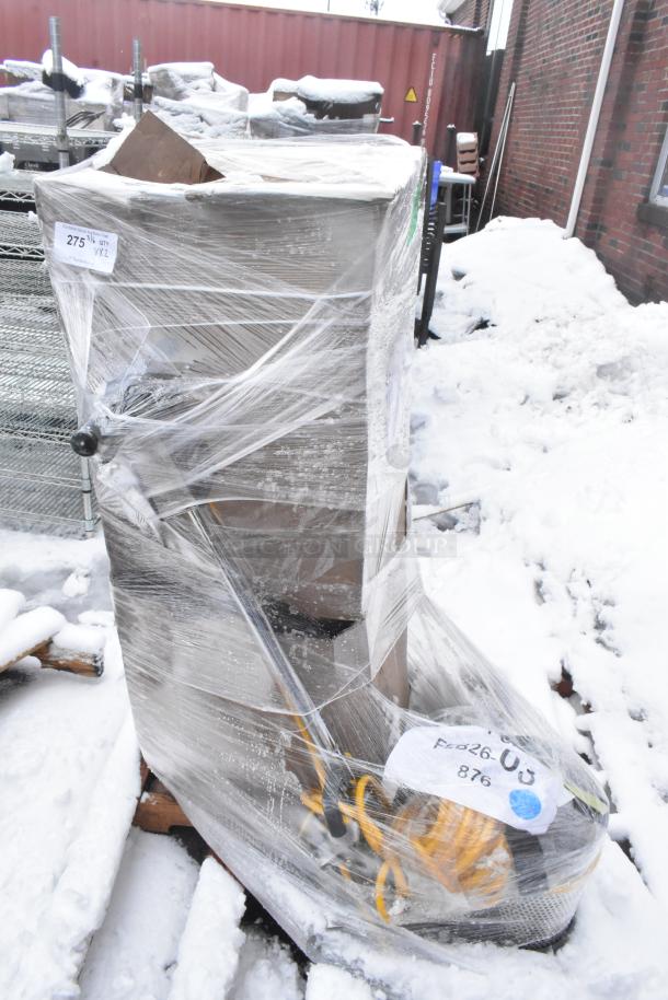 Pallet with floor cleaning machine, brand new but scratch and dent, wrapped in plastic with visible labels and cables.