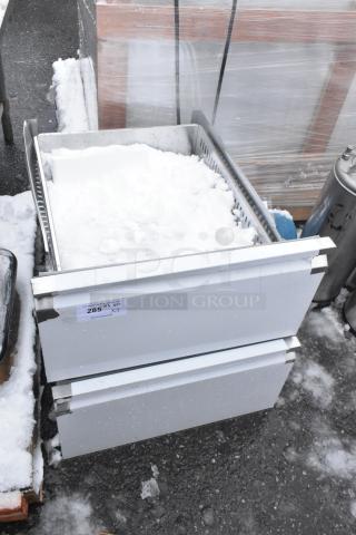 Two brand new scratch and dent metal drawers stacked, label indicating item number 285, outside in snowy conditions.
