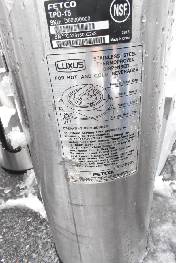 Fetco Luxus TPD-15 stainless steel beverage dispenser for hot/cold drinks. Includes visible labels and operating instructions.