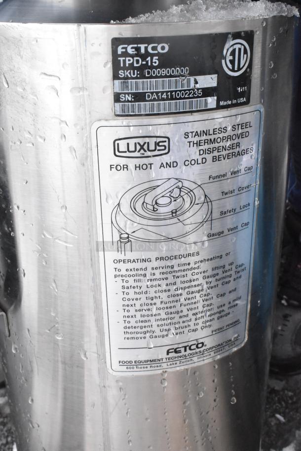 Fetco Luxus TPD-15 beverage dispenser, stainless steel, for hot/cold drinks, visible label with instructions and serial info.