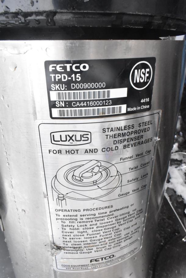 Fetco TPD-15 Luxus stainless steel beverage dispenser for hot and cold drinks, features twist cover, safety lock, operating instructions visible.