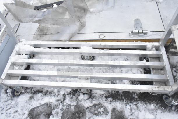 Metal dunnage style cart on casters, featuring a slatted design. Condition shows signs of outdoor use with some snow.