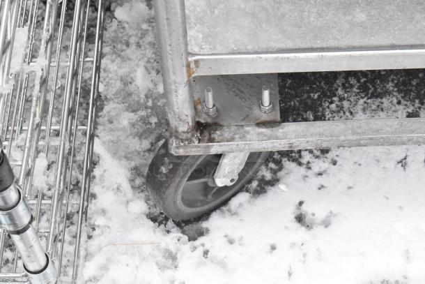2-tier metal cart on commercial casters, showing robust construction. Slight rust visible; designed for heavy-duty use.