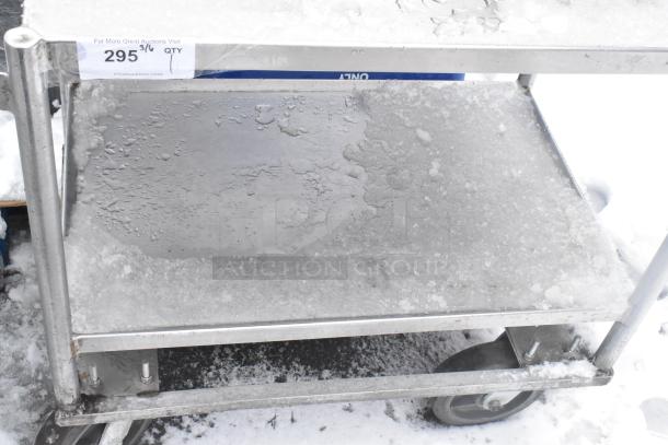 Two-tier metal cart on commercial casters, visible snow covering, sturdy frame, marked with auction label "295 ¾ QTY".