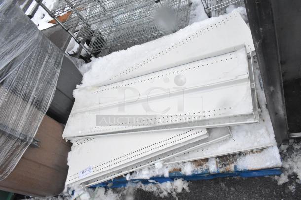 Pallet lot of white metal shelves on a blue pallet, with perforated designs, covered in snow, showing some signs of wear.