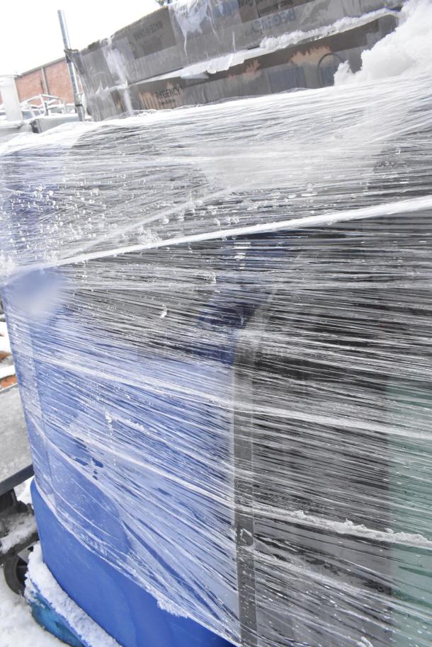 Plastic-wrapped bundle of various items including Regency EG-2436 wire shelf and poly trash bins, partially covered in snow.