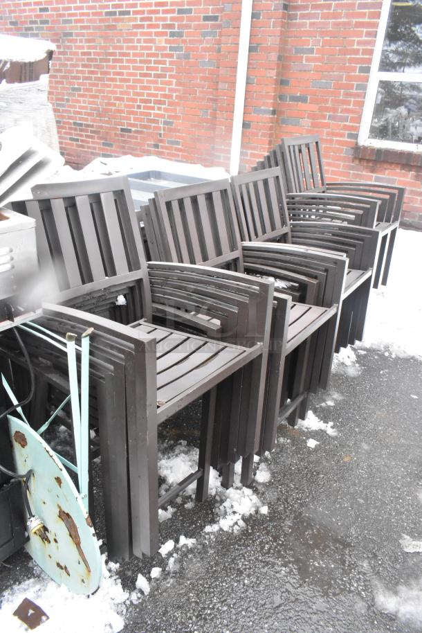 26 stackable brown outdoor arm chairs on pavement, showing wear. Perfect for patio or garden use.