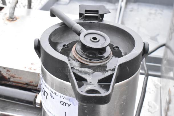 Stainless steel air pot without lid, black spout, visible auction tag. Used condition, signs of wear.