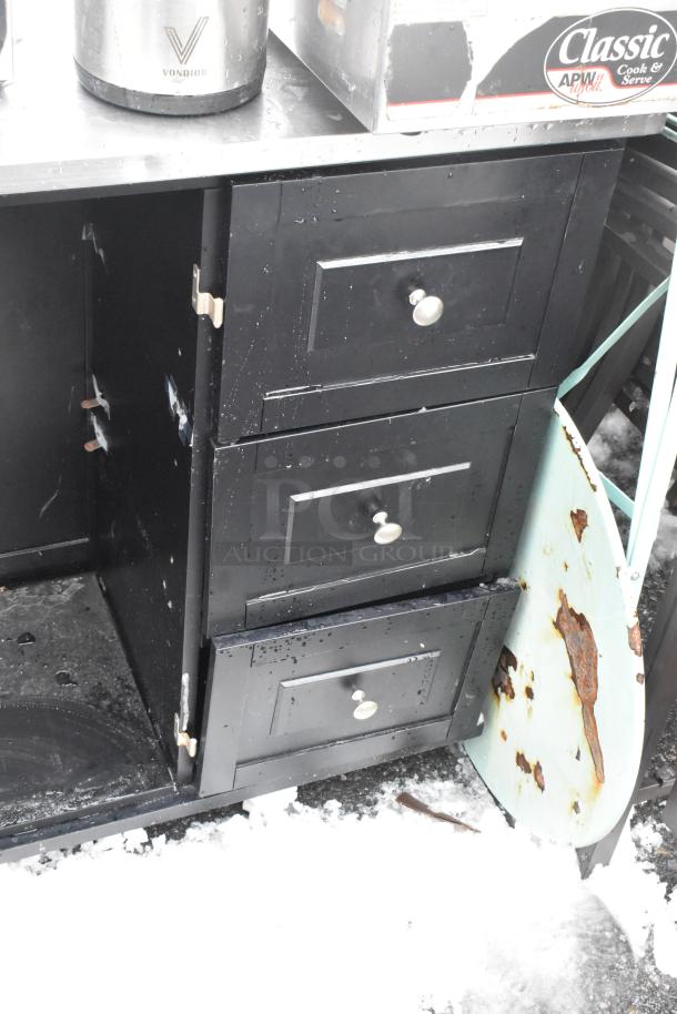 Black cart with three drawers on commercial casters, featuring round knobs. Visible rust and signs of wear.