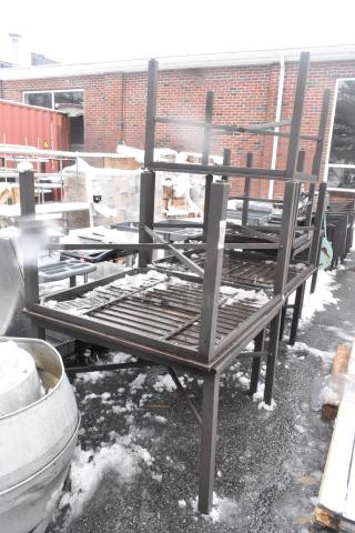 Five brown outdoor patio tables stacked, metal frames, slatted tops, in fair condition with minor wear, visible snow on surfaces.