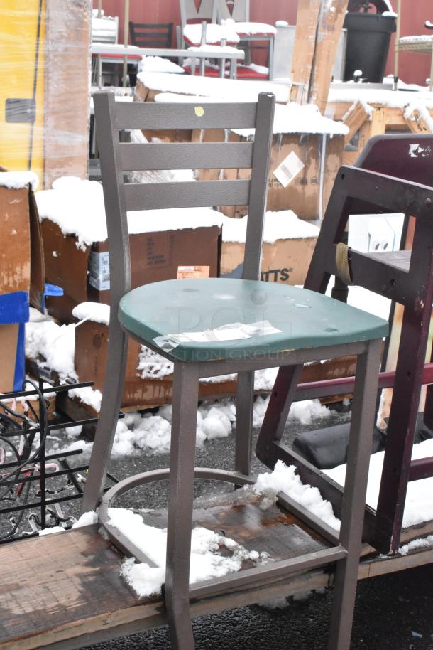 Bar height chair with metal frame and green seat, displayed outdoors. Signs of wear; snow on chair.