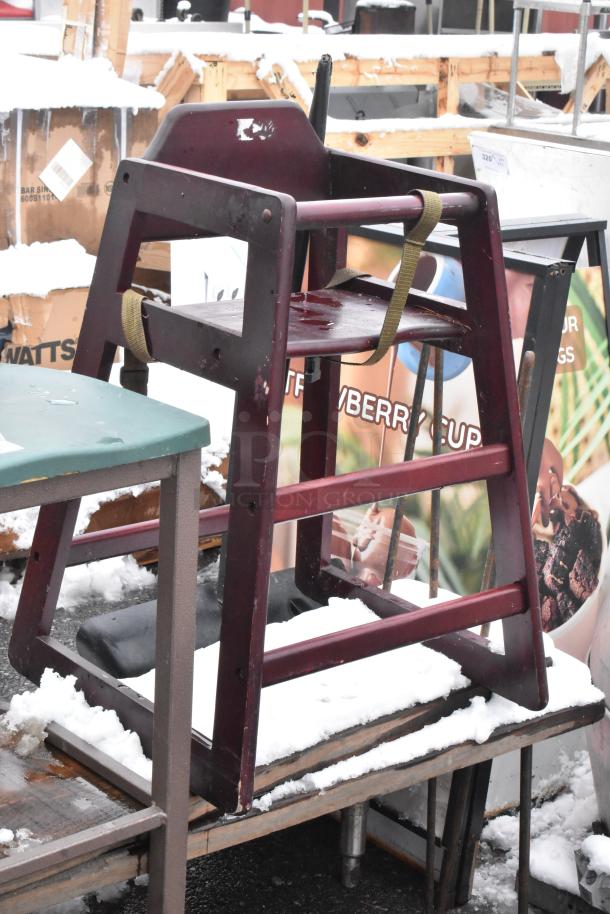 Bar-height chair in fair condition, wooden frame, maroon color. Includes a safety strap. Snow-covered surface.