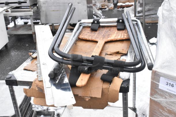 Industrial table on commercial casters with under shelf, includes tray stands and assorted items on top, shown in used condition.
