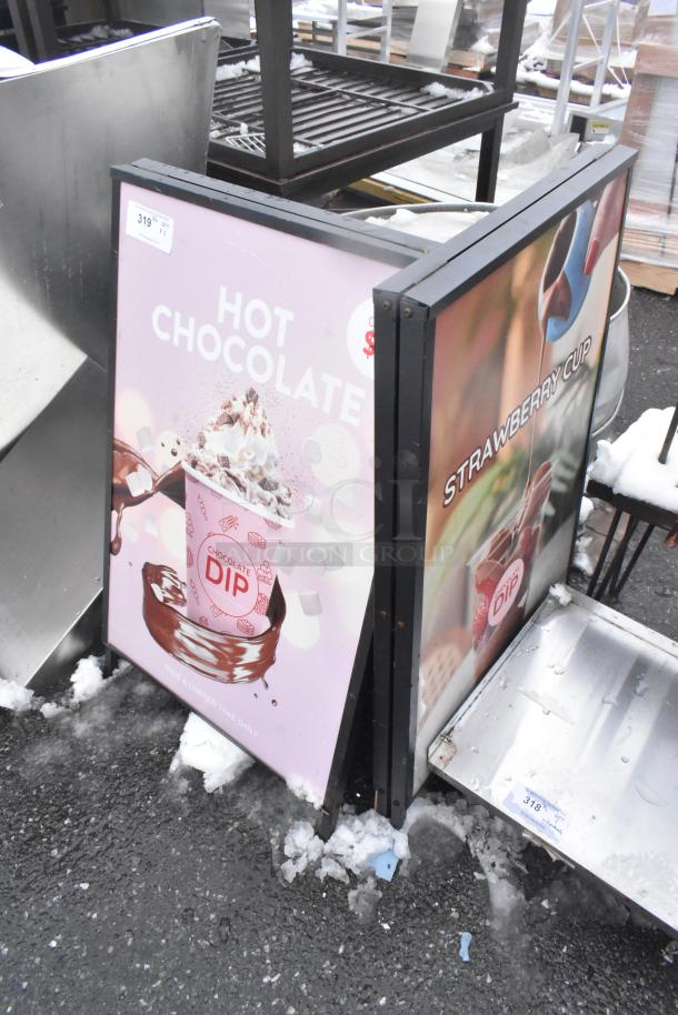 2 A Frame Sidewalk Signs with "Hot Chocolate" and "Strawberry Cup" ads, in good condition, minor snow around base.