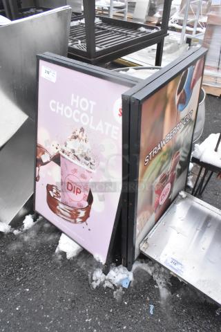 2 A Frame Sidewalk Signs with "Hot Chocolate" and "Strawberry Cup" ads, in good condition, minor snow around base.