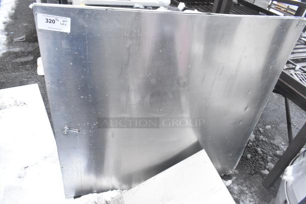 Metal panel with noticeable scratches and dings, attached label "320" indicating auction information, snowy outdoor setting.