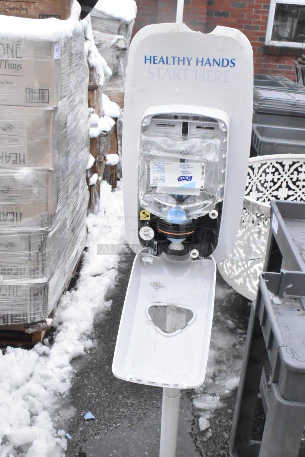 Hand sanitizer dispenser with “Healthy Hands Start Here” sign, outdoor setting. No mop bucket or sign visible.