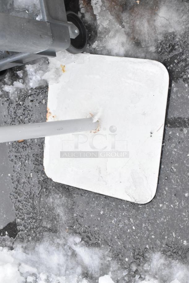 Mop bucket and sign on icy pavement, showing moderate wear. Potential functional value in cleaning or maintenance tasks.